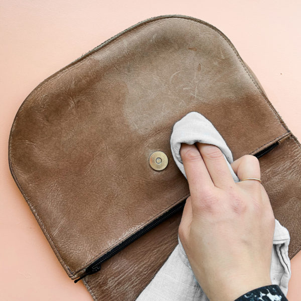 Anwendung der Lederpflegelotion von Kaps auf einer gebrauchten Tasche.
