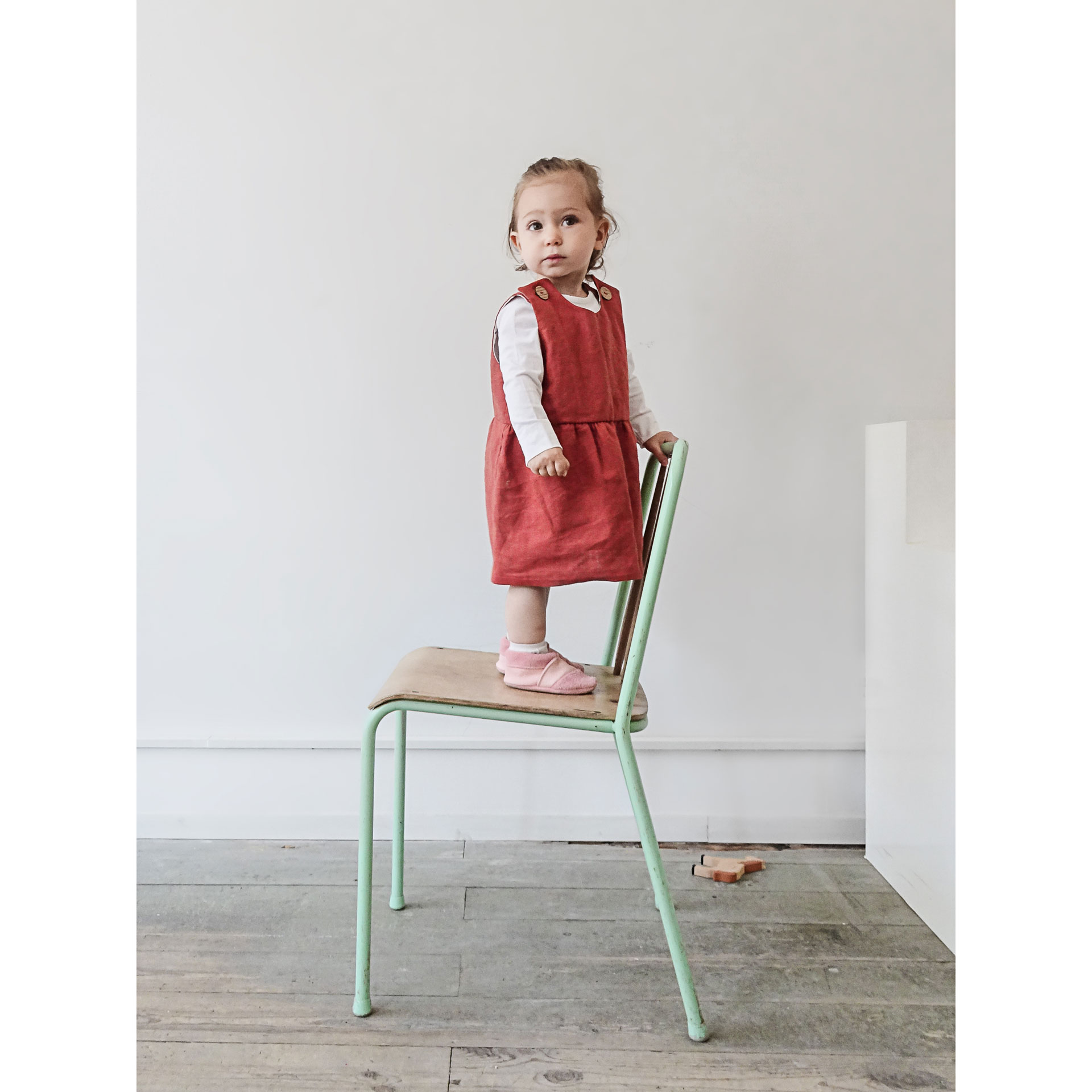 Kind steht auf einem Stuhl und trägt die Lauflernschuhe MOQ in der Farbe Rosa.