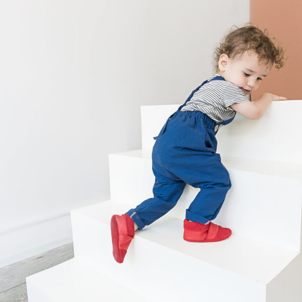 Kind krabbelt Treppe mit den Lauflernschuhen MOQ in der Farbe Rot hinauf.