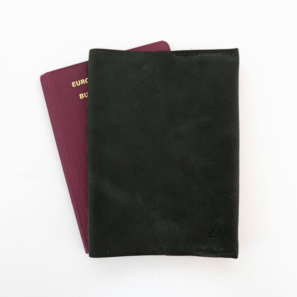 Vorderseite der Reisepasshülle EVE aus nachhaltigem Naturleder in Kohle mit schlichter Logoprägung und Reisepass