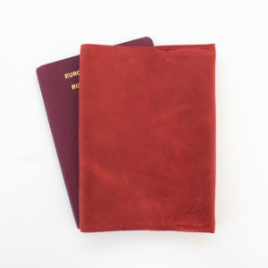 Vorderseite der Reisepasshülle EVE aus nachhaltigem Naturleder in Rot mit schlichter Logoprägung und Reisepass