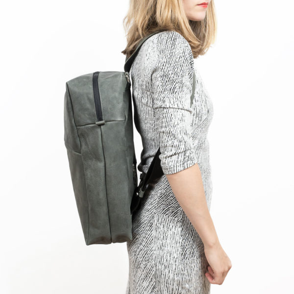 Model trägt Rucksack NEO LARGE aus nachhaltigem Naturleder in Steingrau von der Seite fotografiert