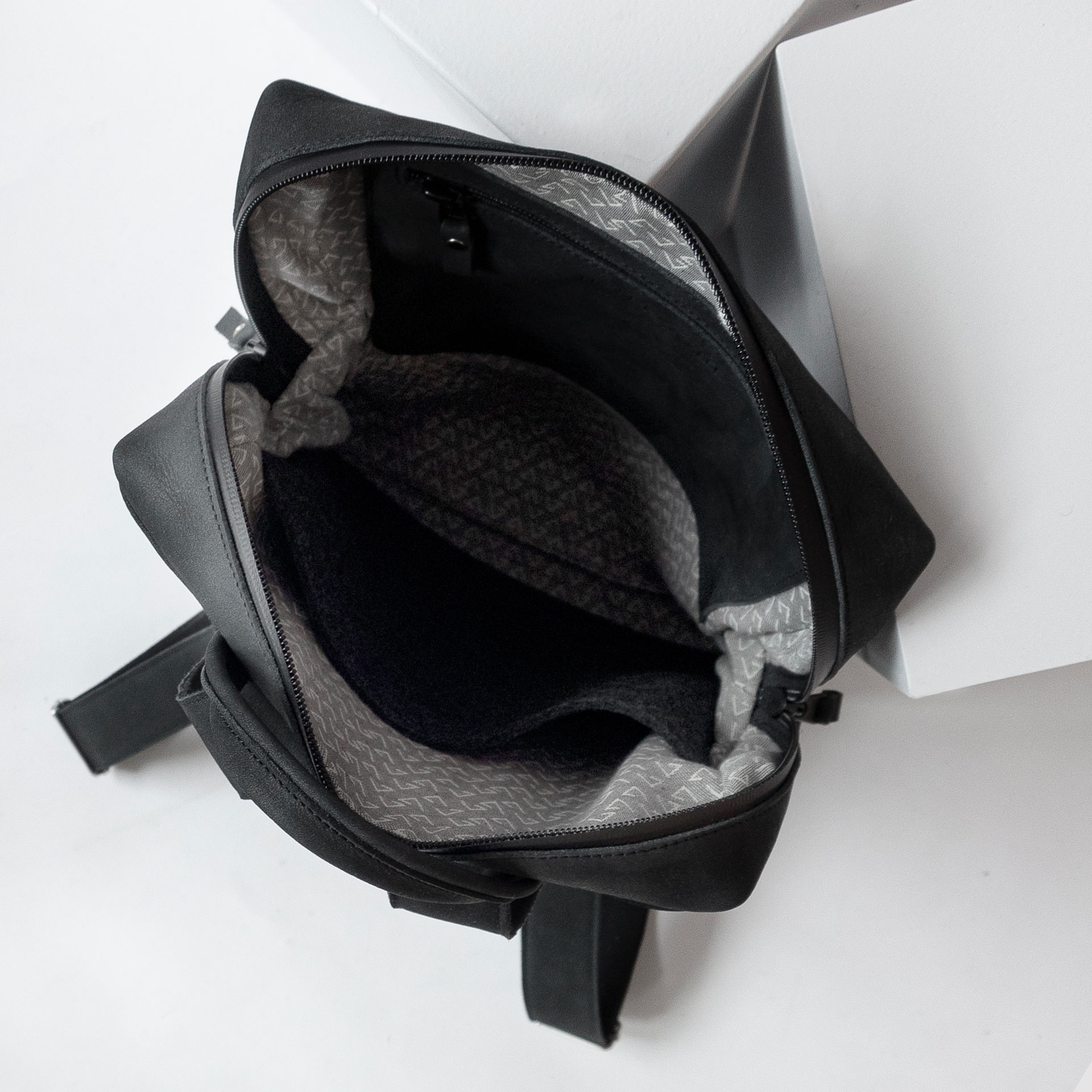 Innenansicht des Rucksacks NEO SMALL aus Naturleder in Kohle mit Futterstoff, Reißverschlusstasche und Laptopfach aus Filz