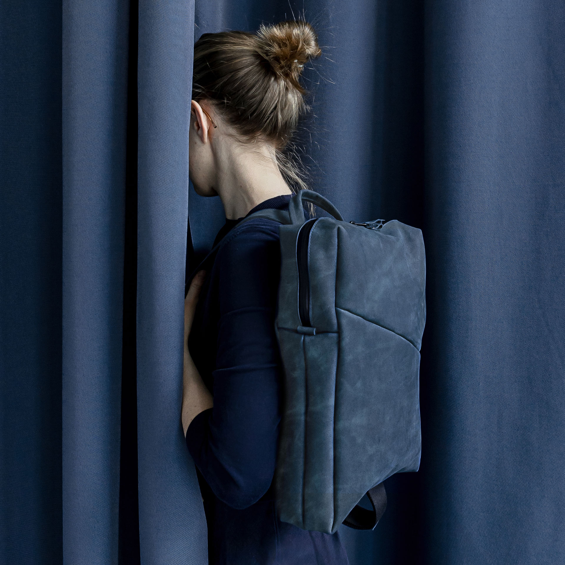 Model trägt Rucksack Neo Small in Dunkelblau aus nachhaltigem Naturleder