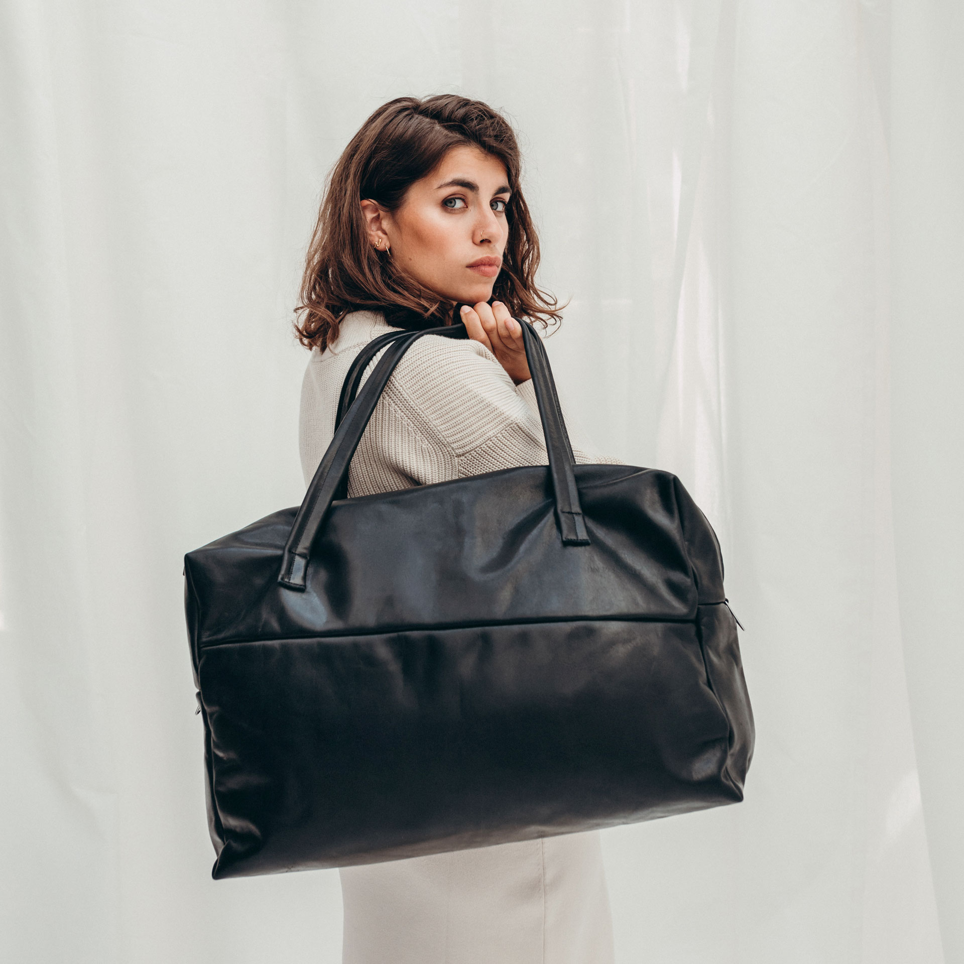 Model mit Weekender Reisetasche RIO mit Henkeln aus schwarzem geölten Naturleder