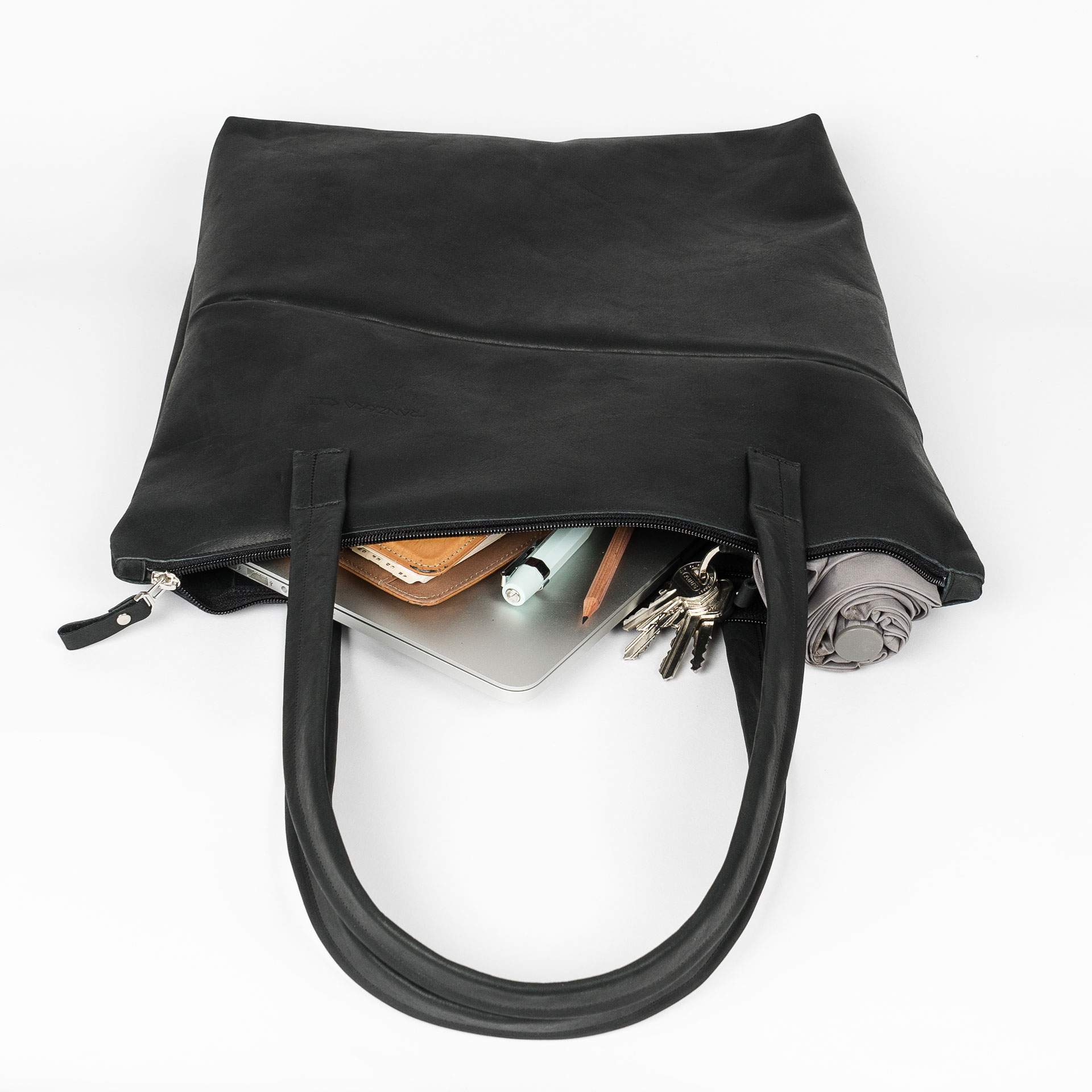 Wickeltasche MIA MIDI aus Naturleder in Kohle gepackt mit Laptop, Notizbuch, Regenschirm und Kleinutensilien