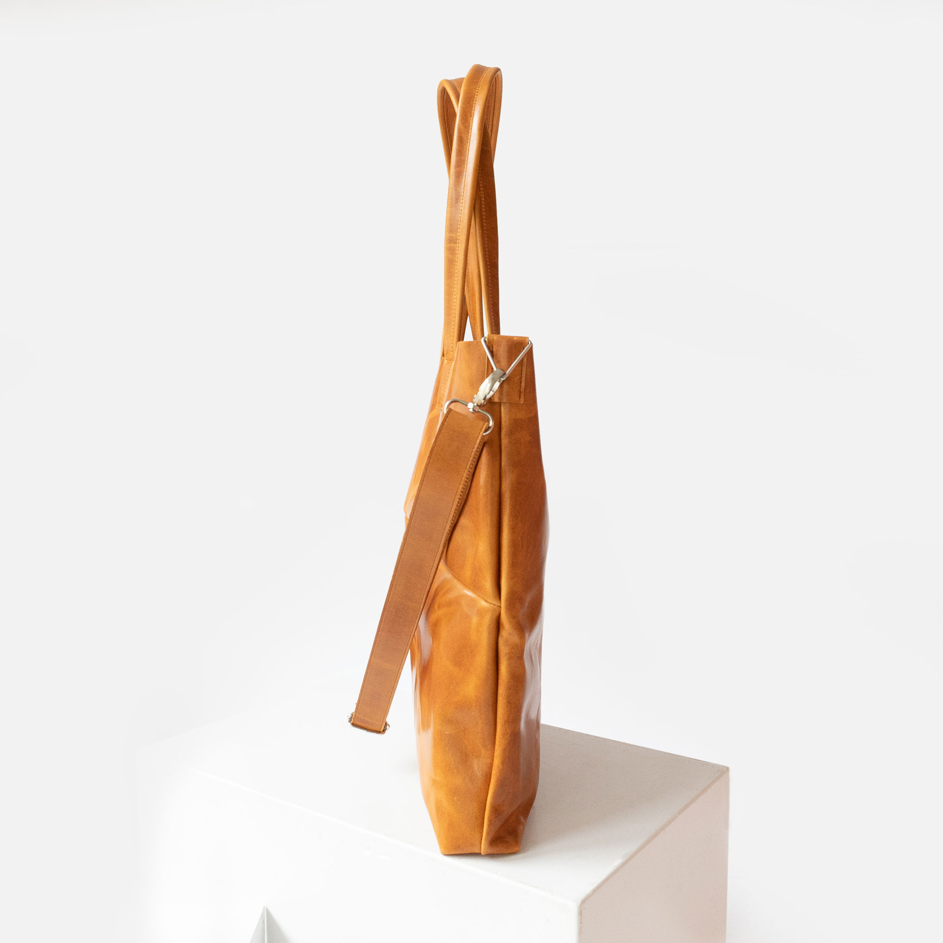 Seitenansicht der Wickeltasche MIA MIDI aus nachhaltigem Naturleder in Cognac geölt mit abnehmbarem Umhängegurt