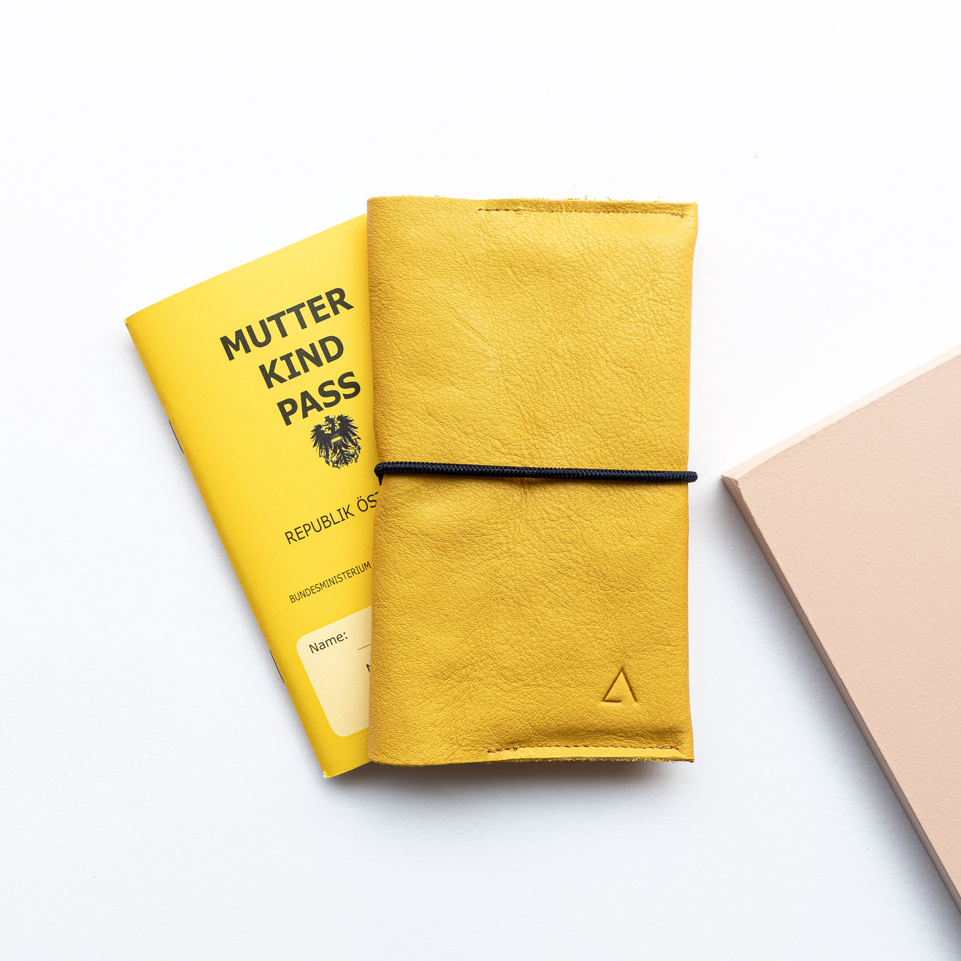 Mutter-Kind-Pass-Hülle EVE Österreich aus Naturleder in Curry mit dezenter Logoprägung und schwarzem Verschlussband