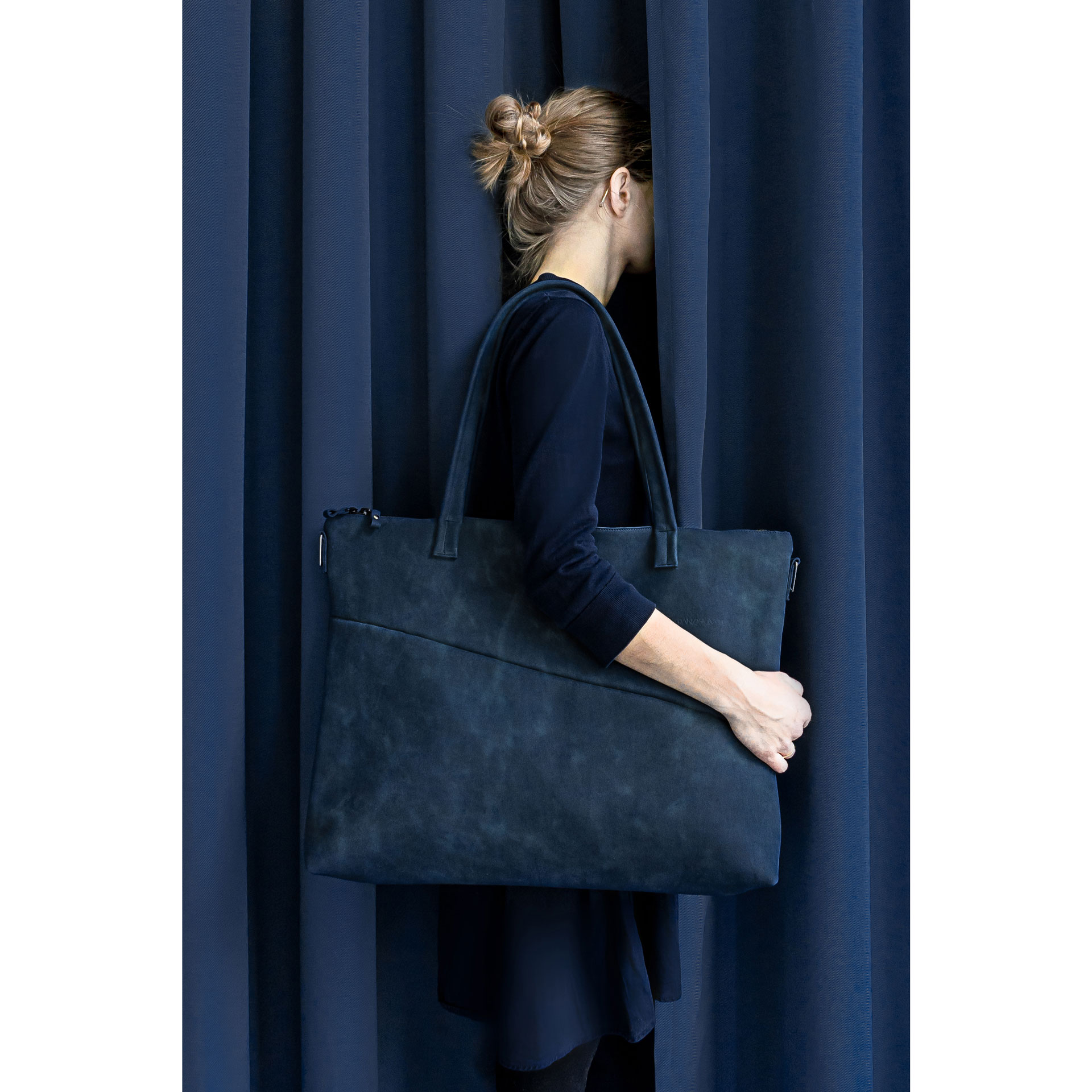 Model vor dunkelblauem Vorhang trägt XXL-Shopper ELA aus Naturleder in Dunkelblau über der Schulter