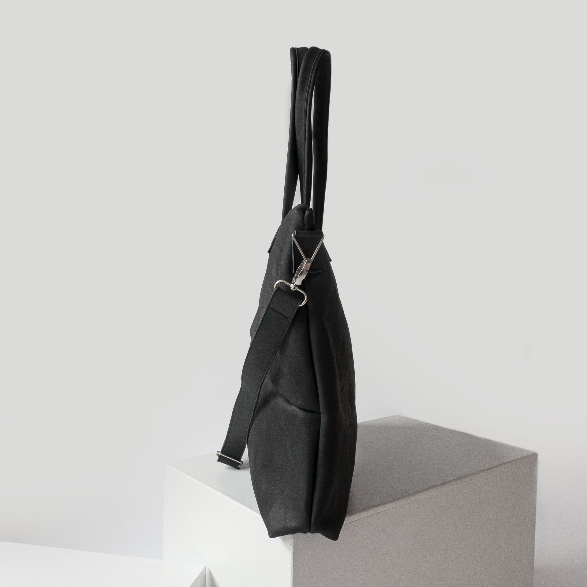 Seitenansicht des XXL-Shoppers ELA aus nachhaltigem Naturleder in Kohle mit langen Henkeln und abnehmbarem Gurt