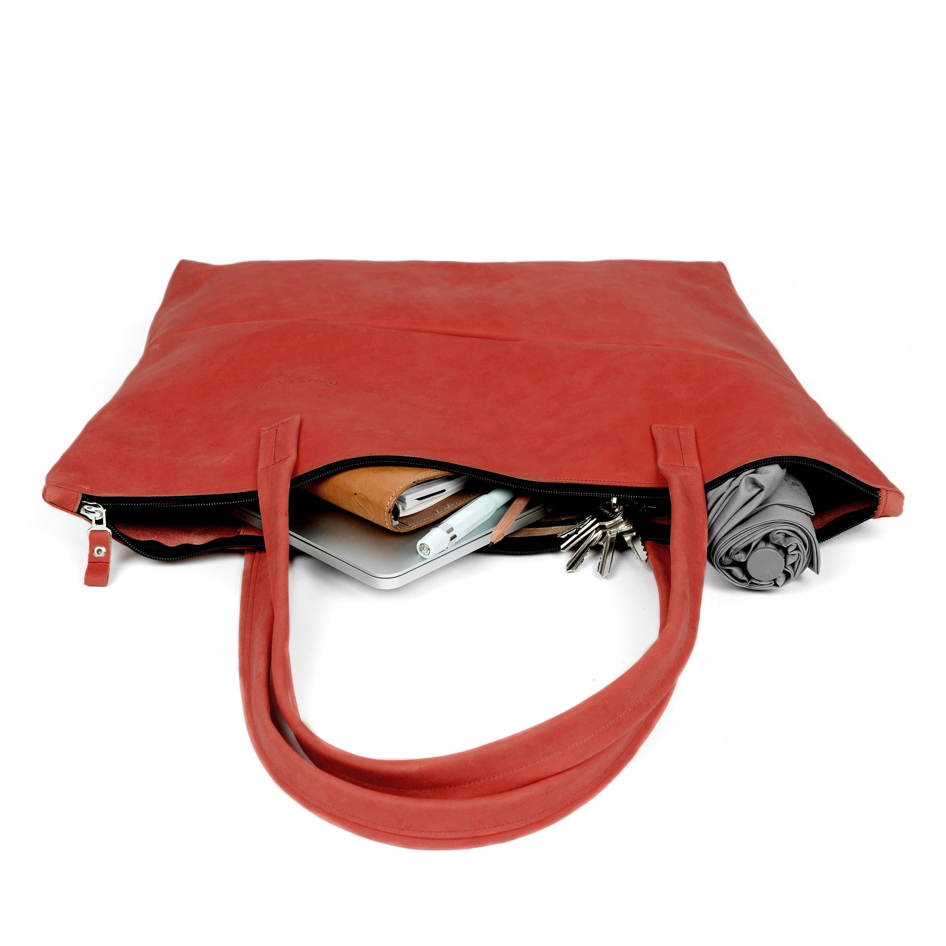 XXL-Shopper ELA aus nachhaltigem Naturleder in Rot gepackt mit Laptop, Notizbuch, Schirm und diversen Kleinutensilien